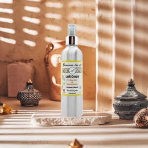 Lait pour le corps Monoï en flacon spray argenté sur socle en pierre, étiquette anglaise montrant “Lait Corps” et ingrédients monoï, aloe vera et avocat.