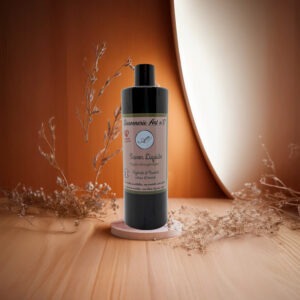Savon liquide biologique hypoallergénique en flacon noir avec étiquette beige, posé sur un petit socle, décor végétal sec et fond orange clair.