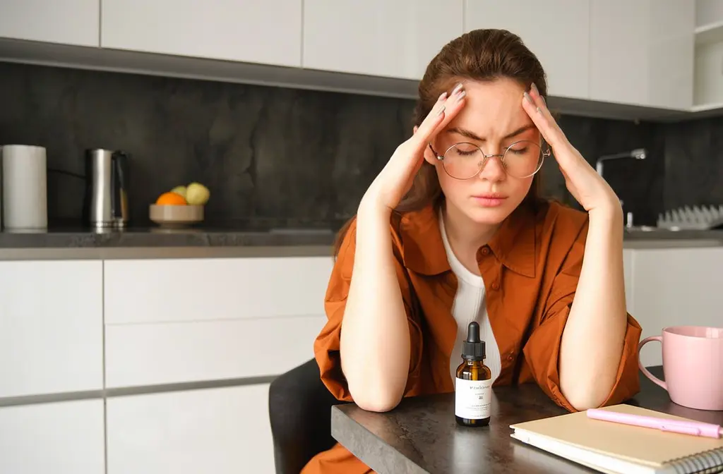 Femme dans une cuisine qui a mal à la tête