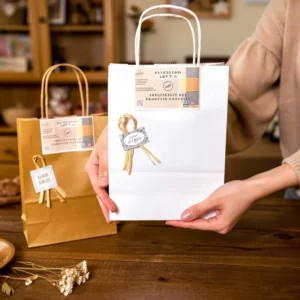 Sac cadeau blanc élégant avec ruban doré et étiquette “Savonnerie Art n'O” – présenté en boutique.