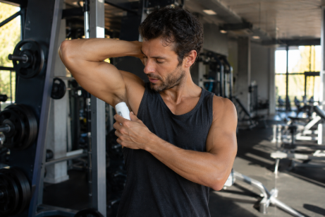 un homme qui applique le meilleur déodorant naturel. Il est dans une salle de sport le matin.